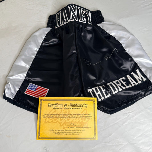 Black and white boxing shorts signed by Devin Haney, accompanied by a Certificate of Authenticity (COA).